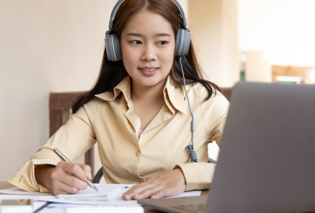 Working professional jotting notes during an online meeting.