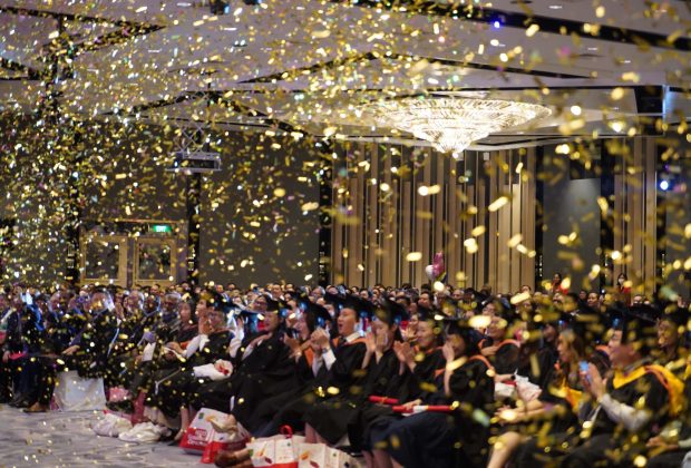 confetti poppers fill the room as the emcee congratulates the graduates on their achievements.