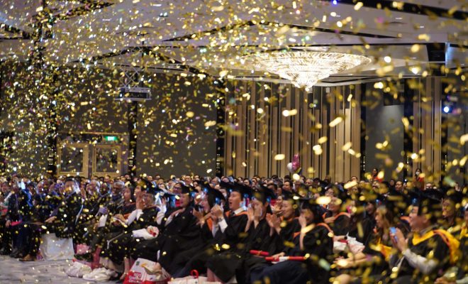 confetti poppers fill the room as the emcee congratulates the graduates on their achievements.