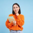 A student thinking about her future while holding notebooks in her hand.
