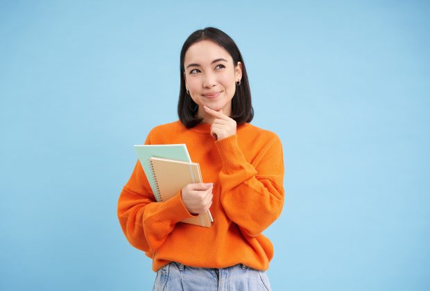 A student thinking about her future while holding notebooks in her hand.