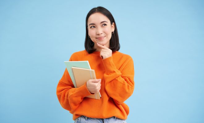 A student thinking about her future while holding notebooks in her hand.