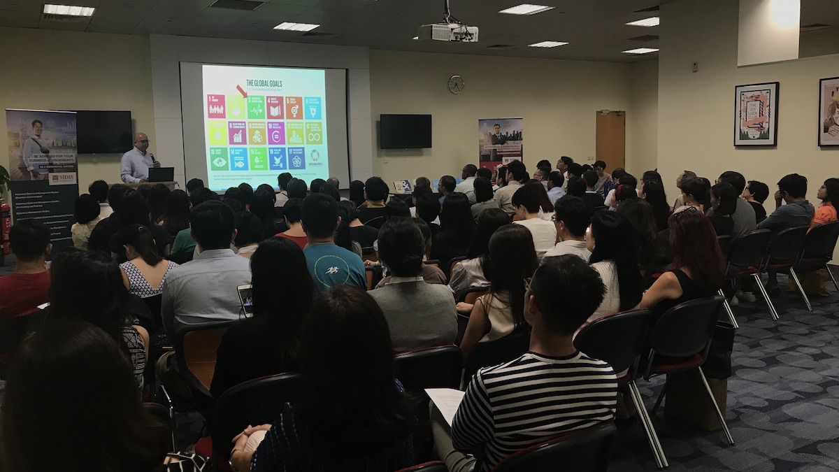 A speaker sharing about global goals of business with students.