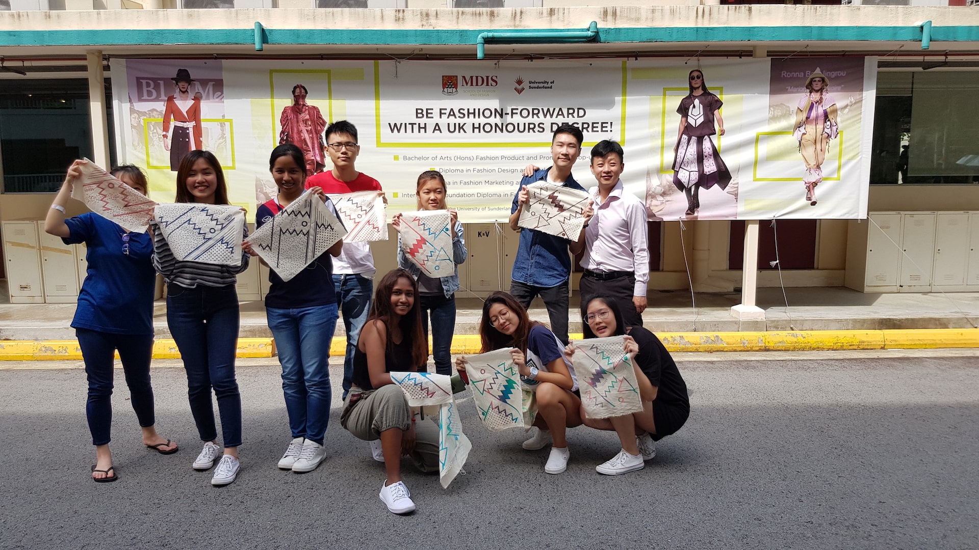 MDIS college students posing with their finished artwork outside of the fashion lab.