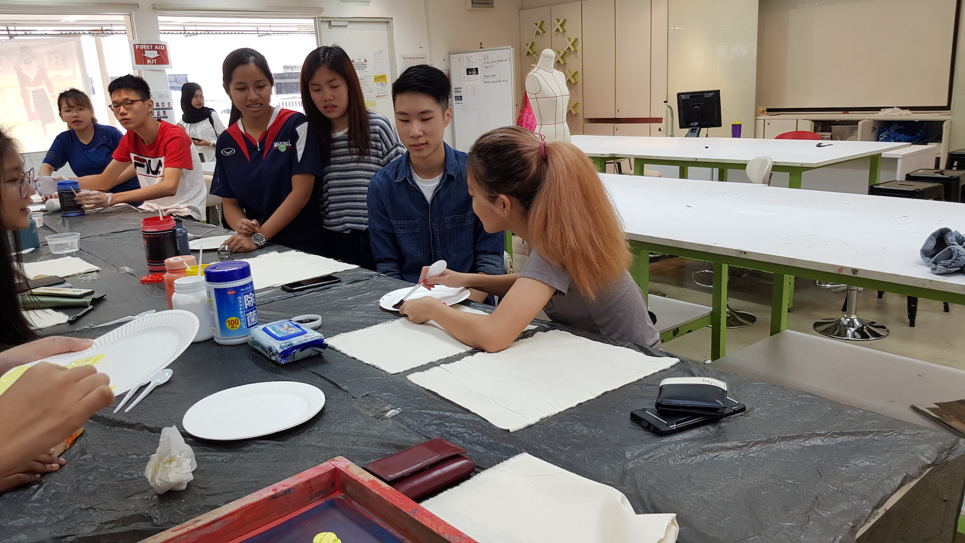 MDIS college students engaging in some art work in the fashion lab.