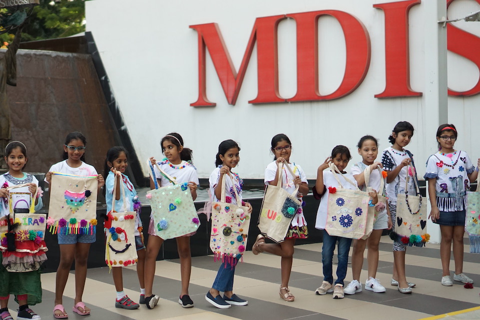 Children showcasing the bags they designed at MDIS fashion lab.