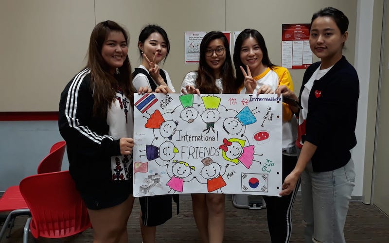A group of MDIS students pose with a banner saying 'International Friends".