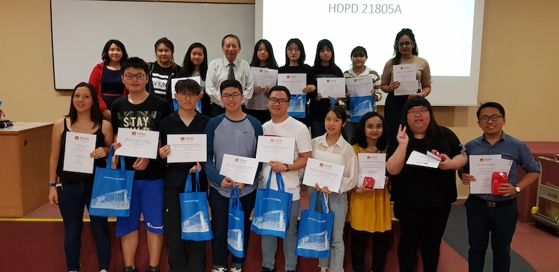 A group of students holding their participation certificates in the lecture theatre.