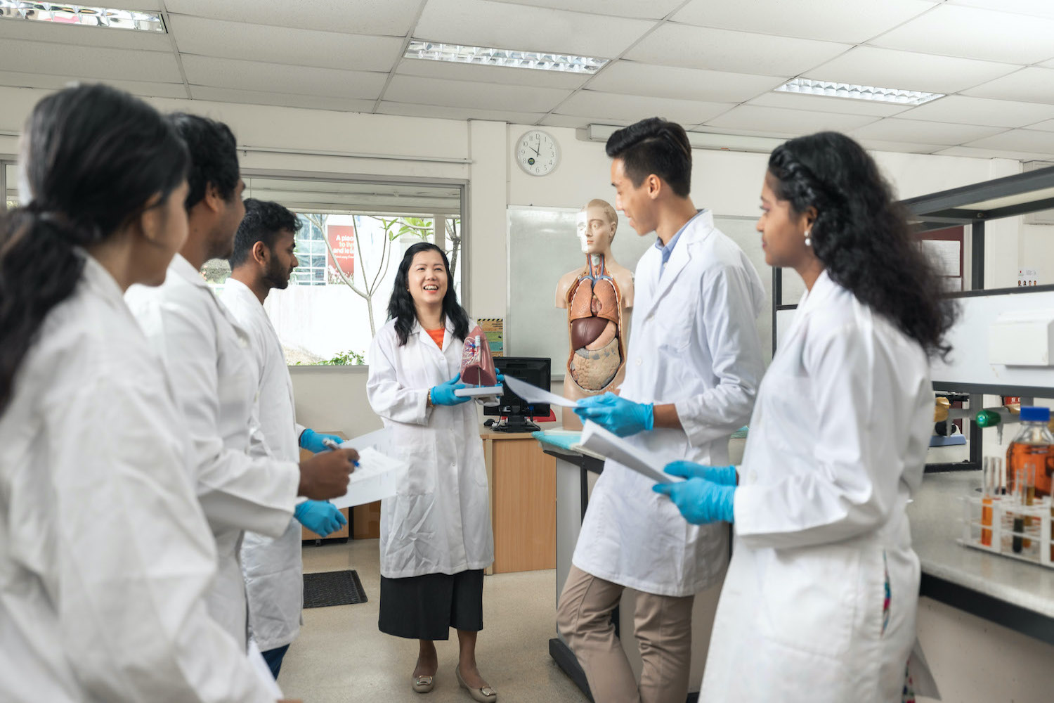 A life science lecturer guiding students in the science lab.