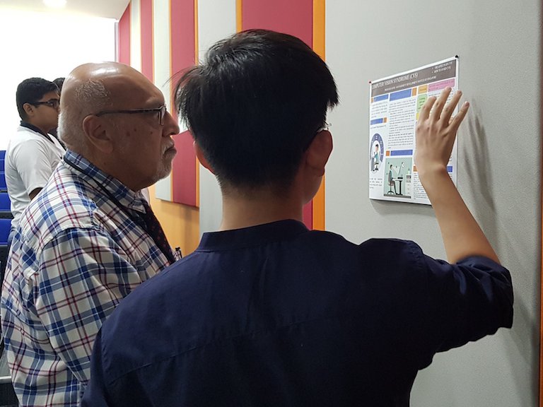 MDIS student explaining his poster to his lecturer.