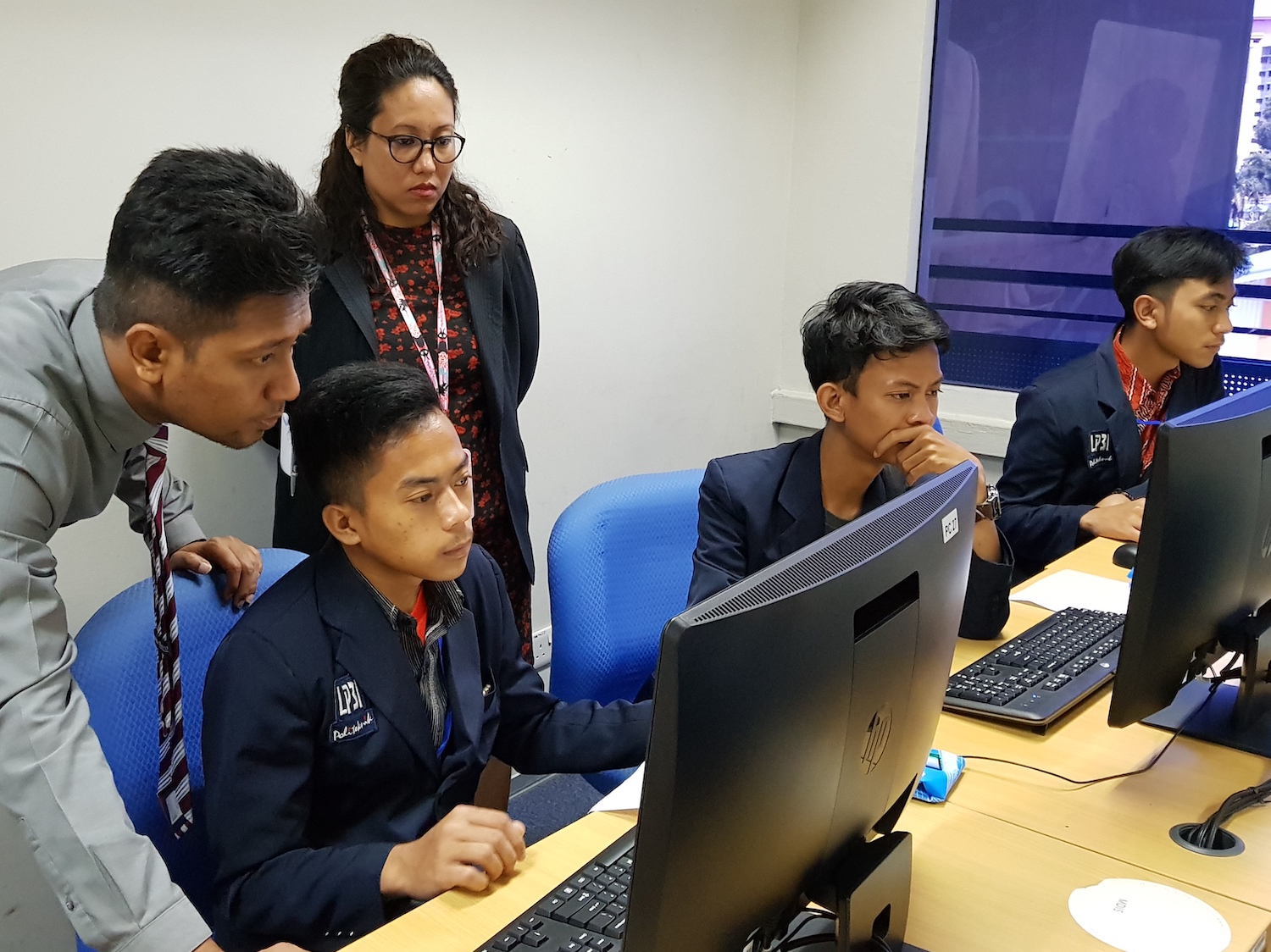MDIS lecturers helping a student with technical difficulties on the computer.