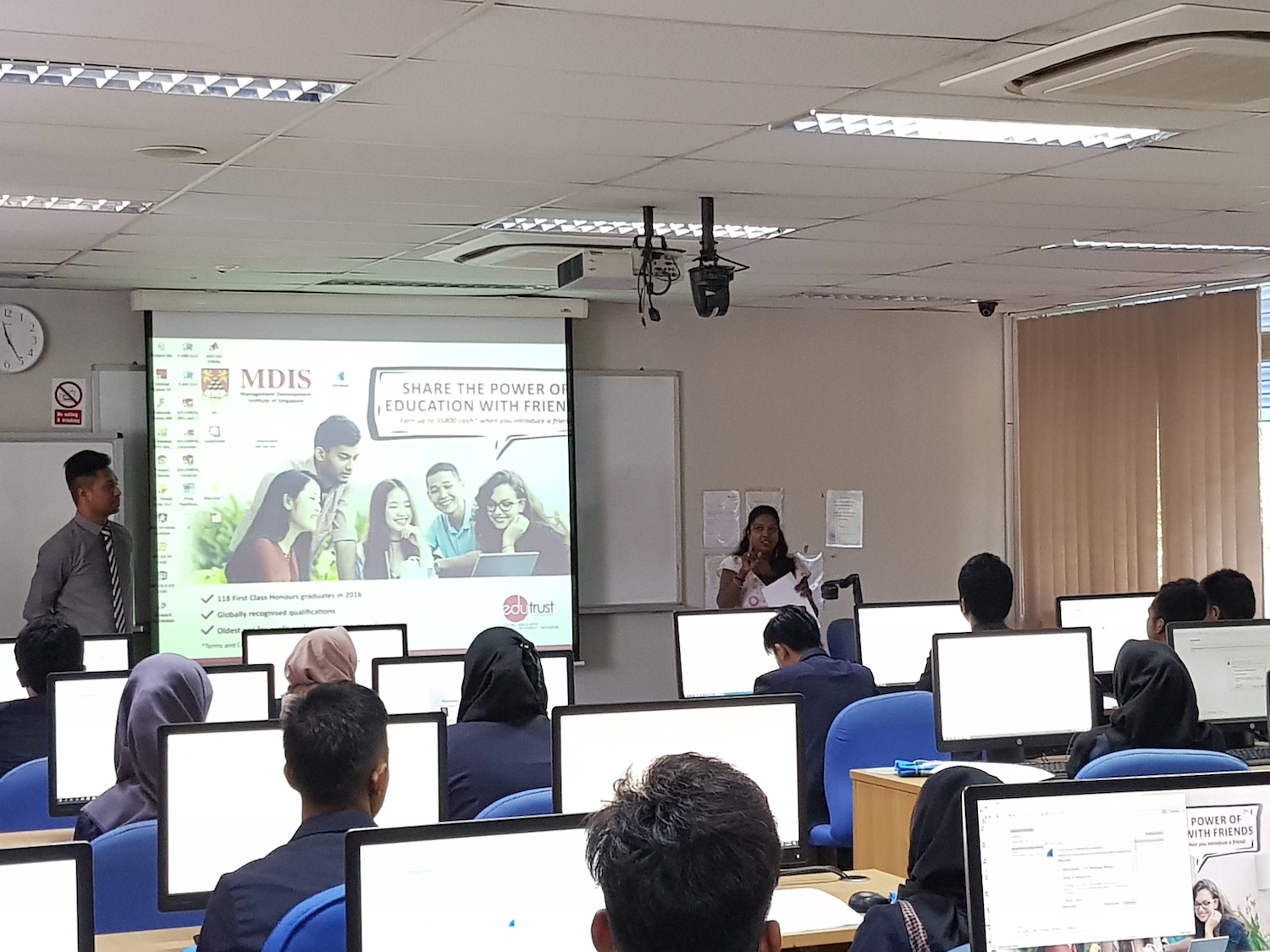 MDIS lecturer speaking to students in a computer lab.