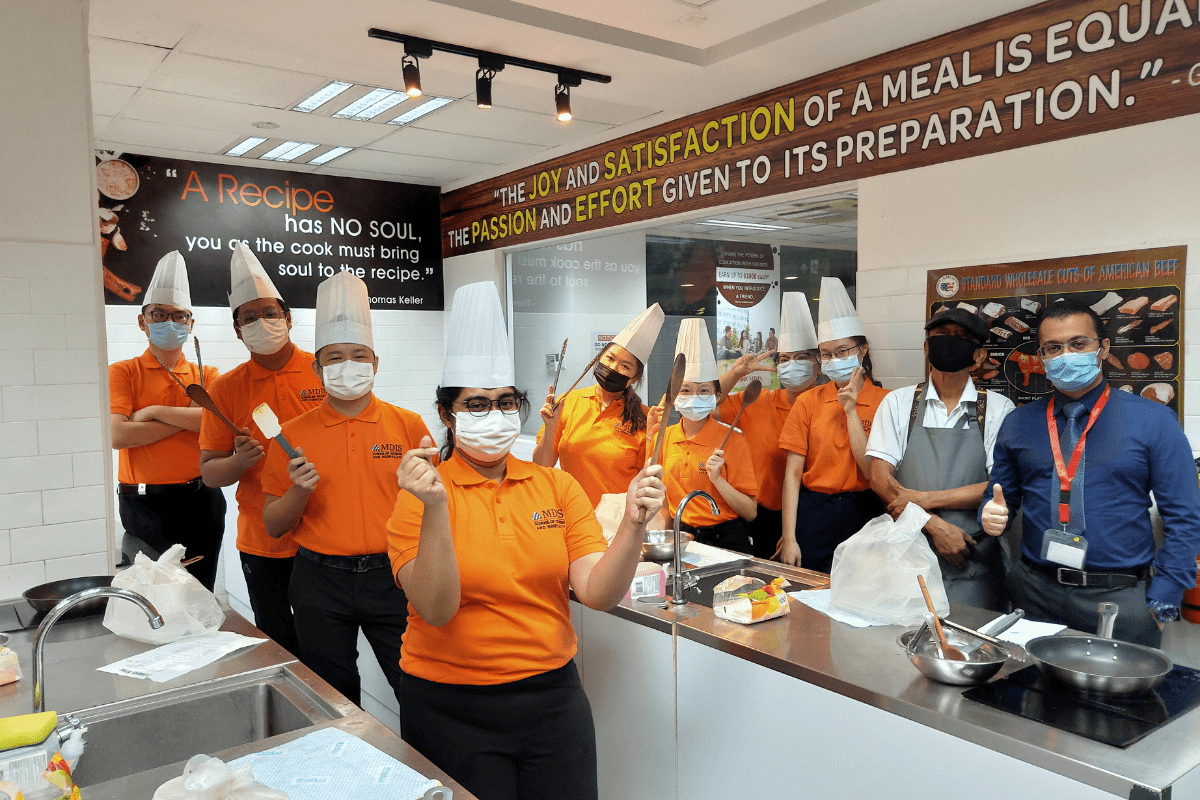 MDIS students posing for a picture with kitchen tools.